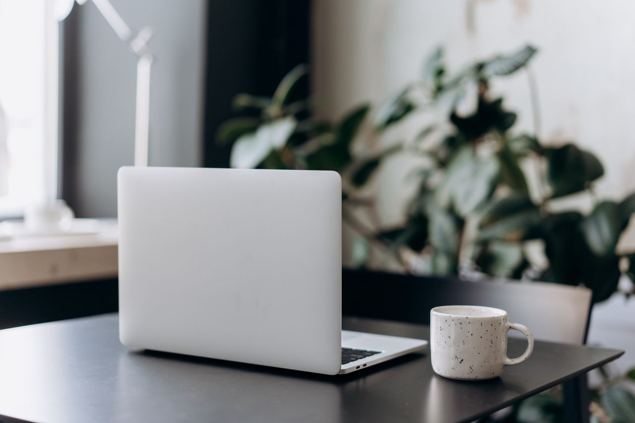 A minimalist workspace featuring a closed laptop and a coffee cup on a table, offering a serene and focused atmosphere.
